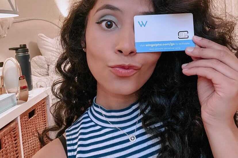 A happy new Wing user holds her SIM card for a selfie.